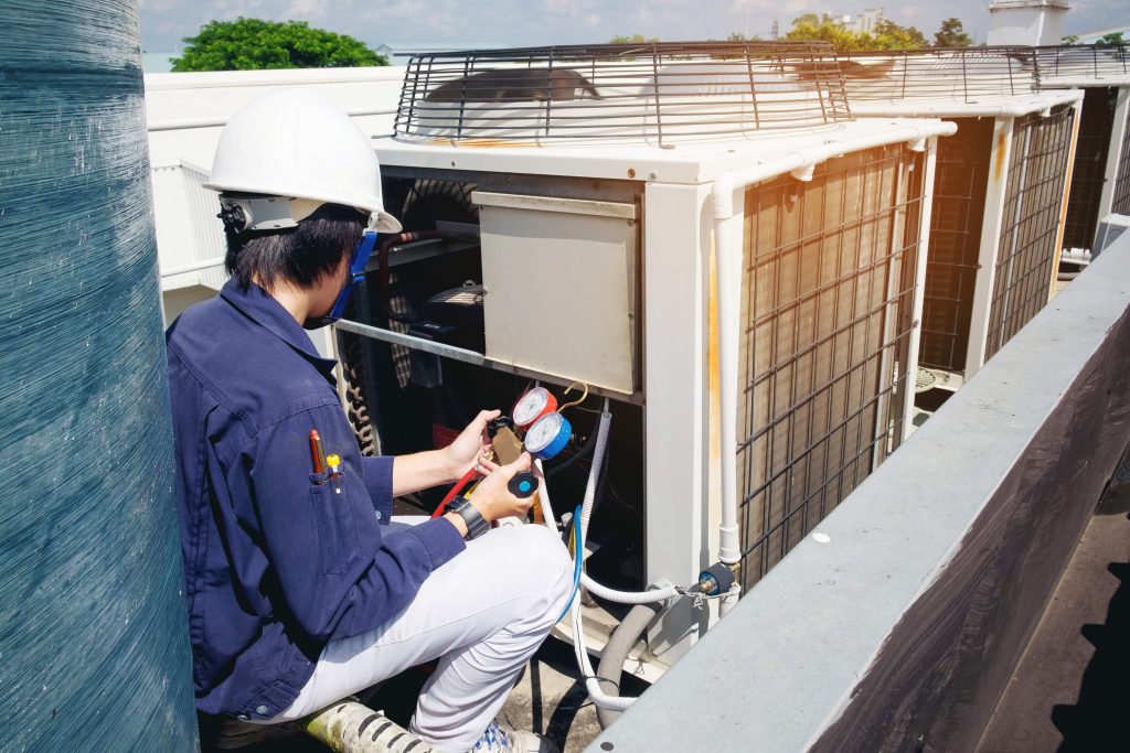 L-Cool technician using a pressure gauge to measure aircon gas levels, ensuring precise top-up.